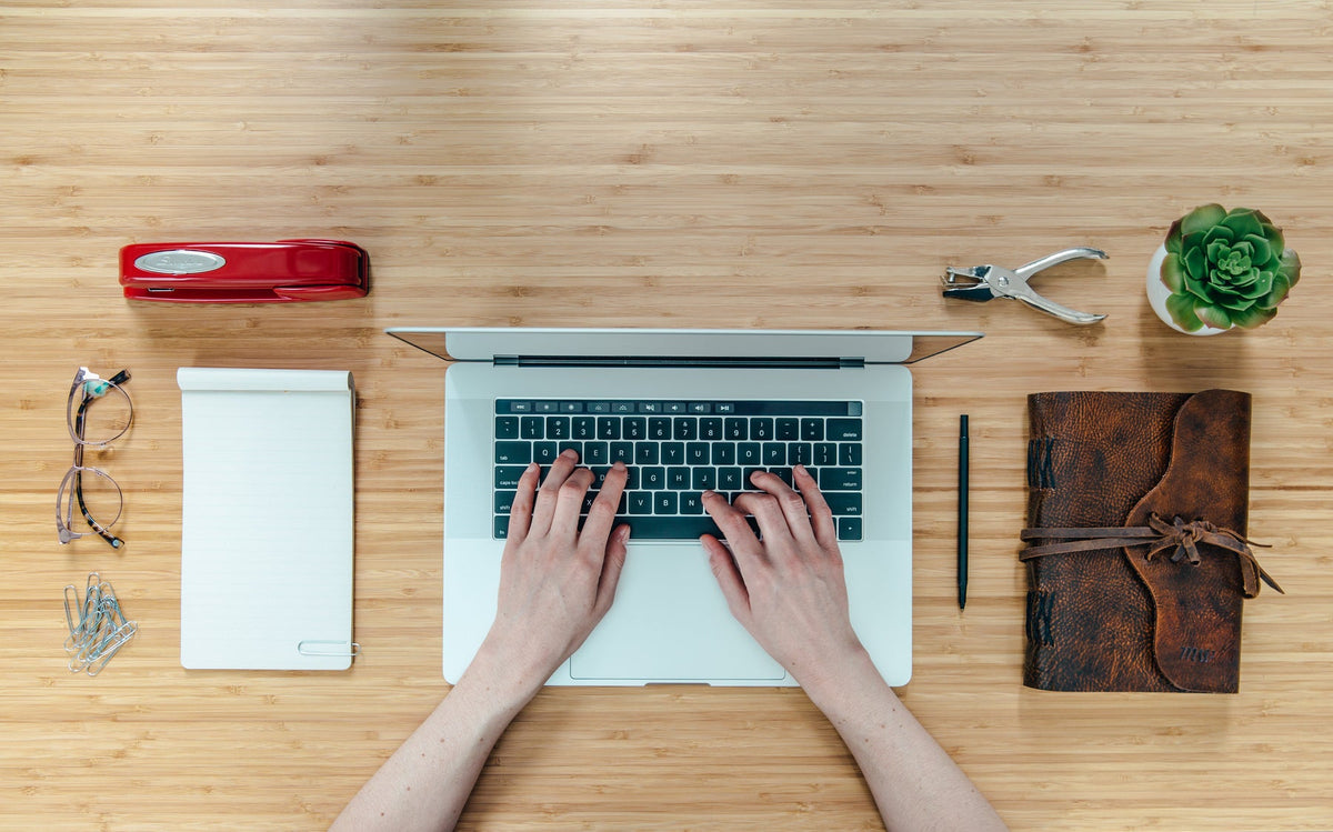 Illustrative laptop workspace with glasses and notebook; Matthew Henry / Burst